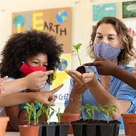 child and teacher holding small potted plants